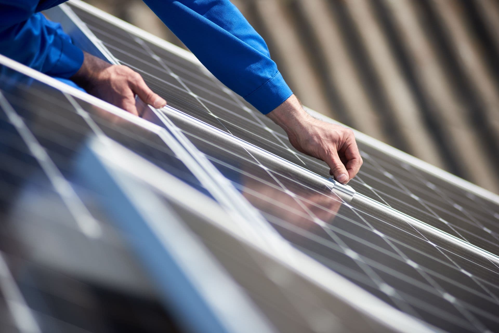 A person in a blue shirt adjusts solar panels on a sunny day. The scene conveys precision and focus, highlighting clean energy technology.