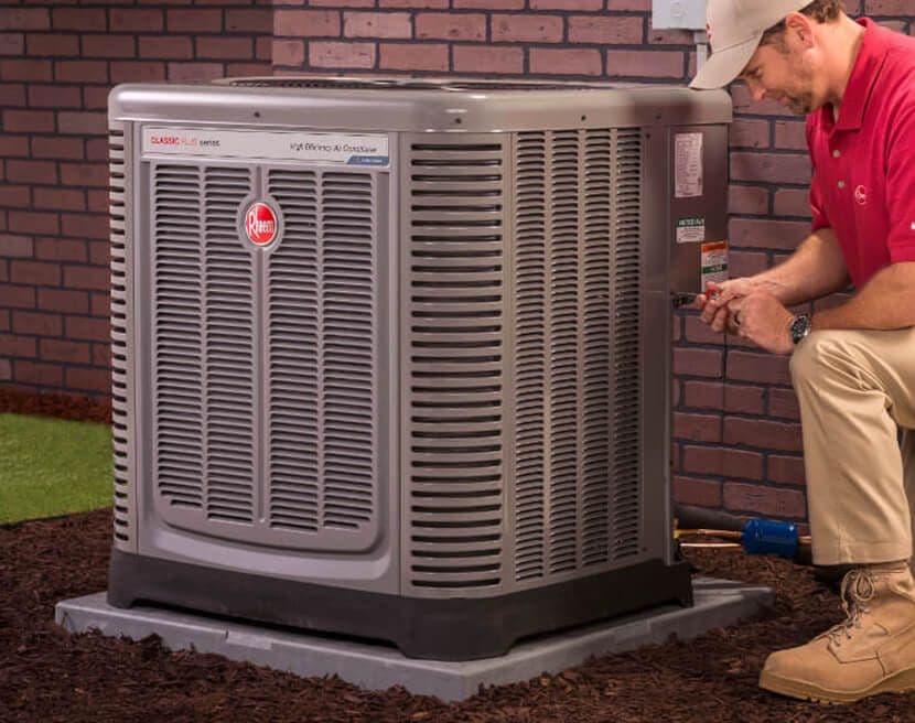 A worker installs a Rheem air conditioning unit.