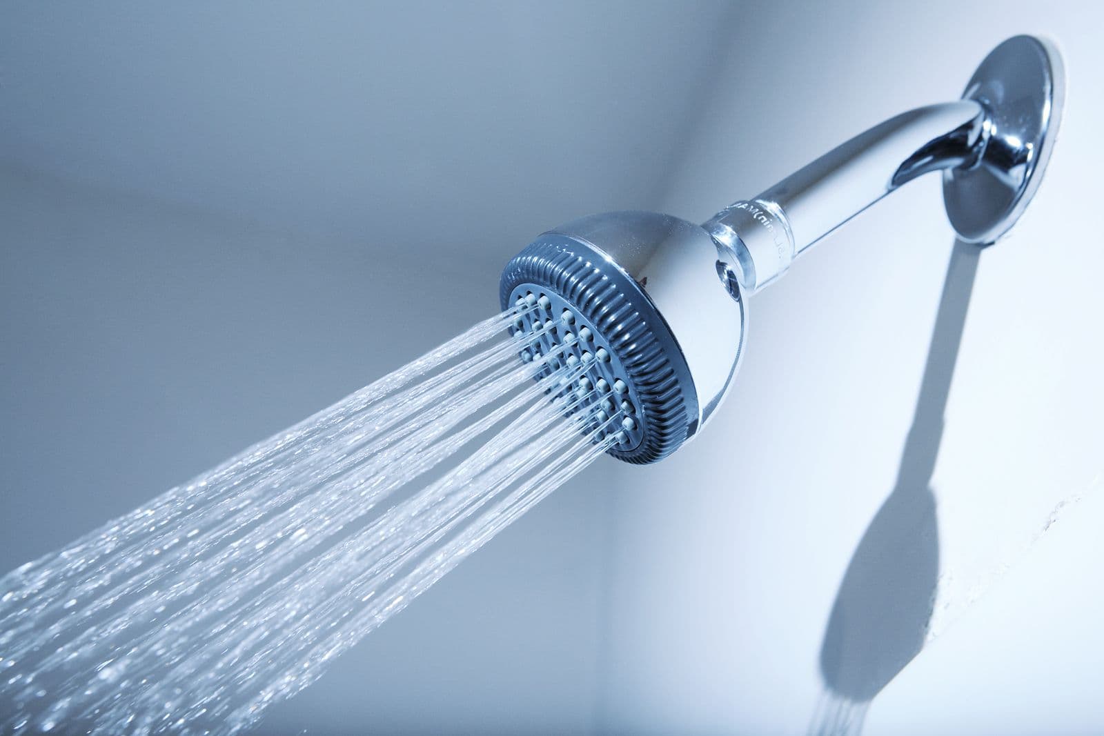 A close-up of a showerhead with water streaming out.