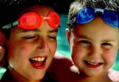 Two children wear goggles in a pool.
