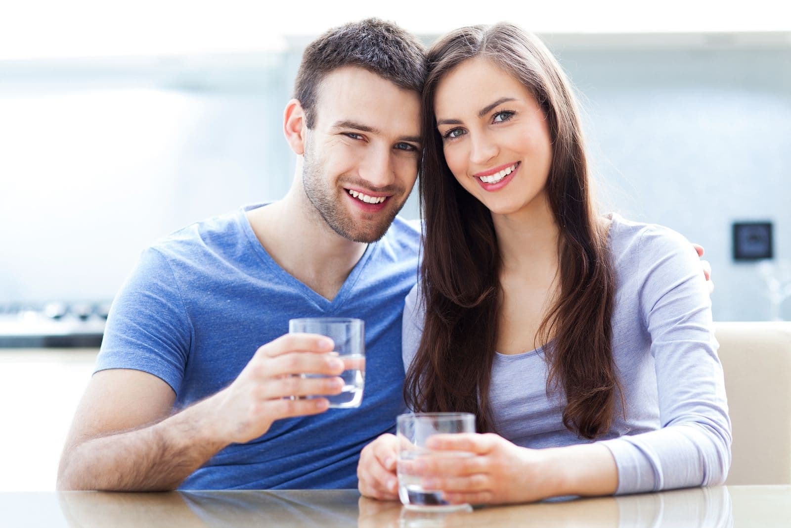 A couple hold glasses of water.